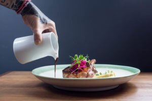 chef sirviendo aderezo en platillo gourmet
