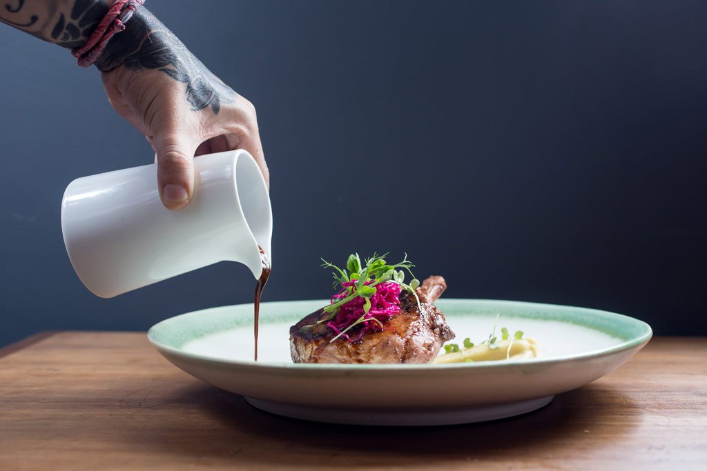 chef sirviendo aderezo en platillo gourmet